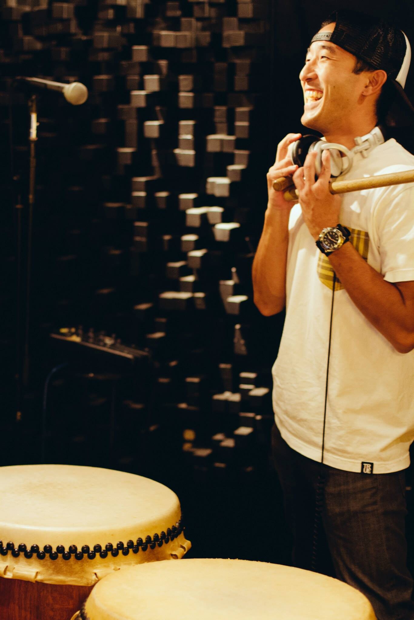 Michael Gonhata smiling with headphones and bachi beside taiko drums